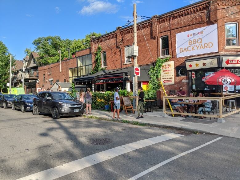 Brick building with a small fenced patio running beside a street.