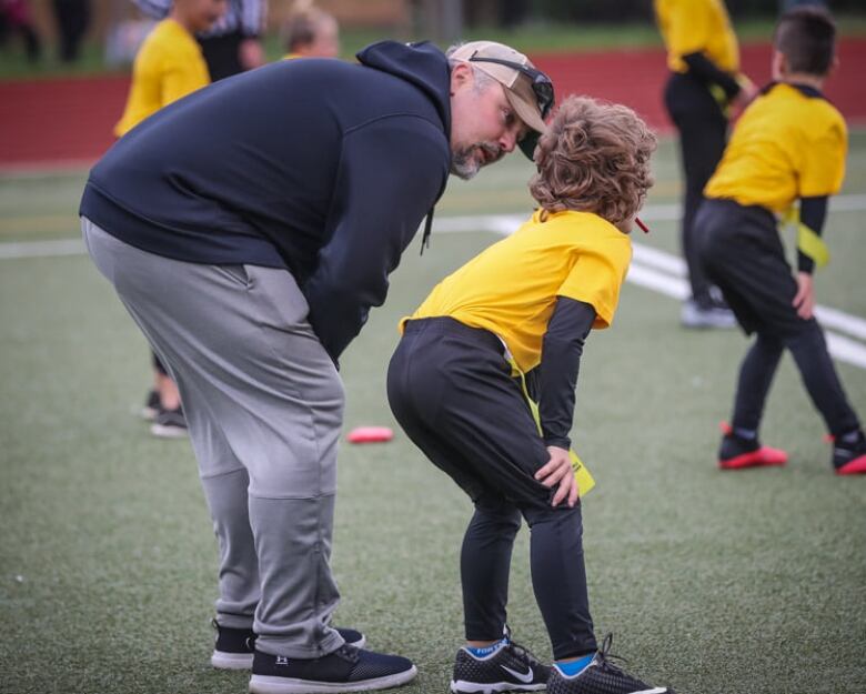 A coach gives advice to a young football player.