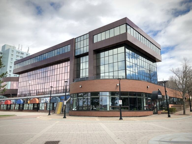 A tall building with lots of windows and a curved red brick front is shown.