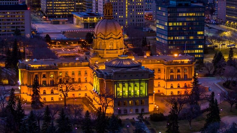 The Alberta legislature is in the foreground of a landscape photo of downtown Edmonton.