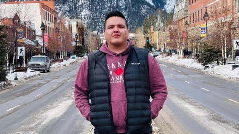 A man poses for a photo in front of a snowy mountain vista.