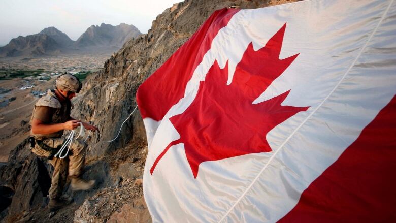 Jeff Wright is seen marking Canada Day by hanging the flag on a mountainside above the forward operating base of Ma'sum Ghar on July 1, 2007. Wright was also honouring his father, also a soldier, who served in Bosnia and gave the flag to his son to take to Afghanistan.