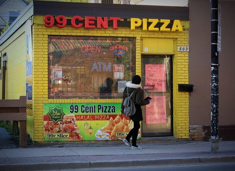 A person is seen walking into a pizza shop.