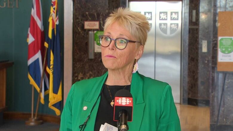 A woman wearing glasses and a green blazer stands in Newfoundland and Labrador's Confederation Building.