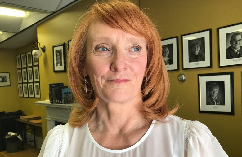 Woman with red-blonde hair cut at shoulder in white shirt.