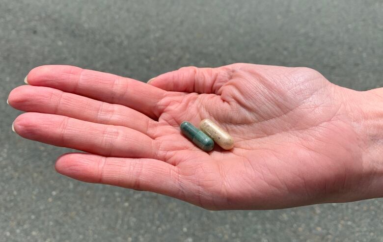 A hand holds out two pills containing psilocybin.