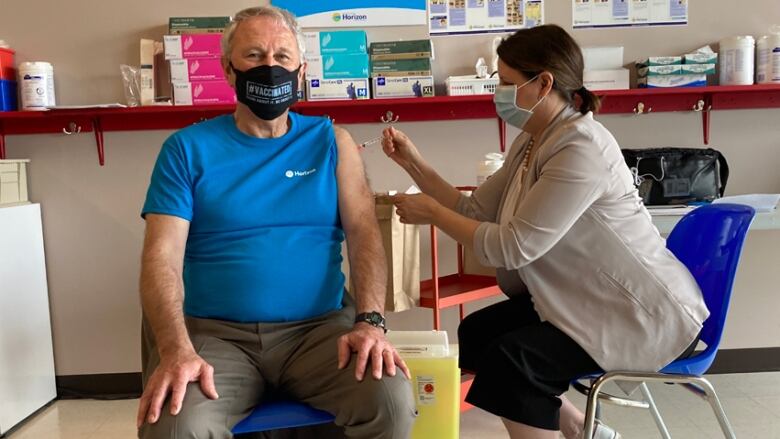 A woman gives a man a needle.