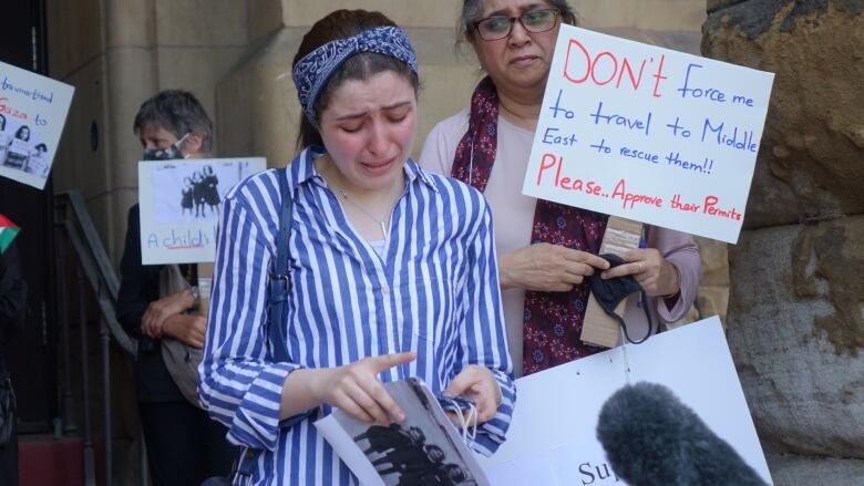 A woman cries as she holds a petition outside a politician's office.