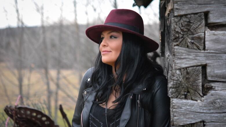 A woman wearing a leather jacket and a maroon hat.