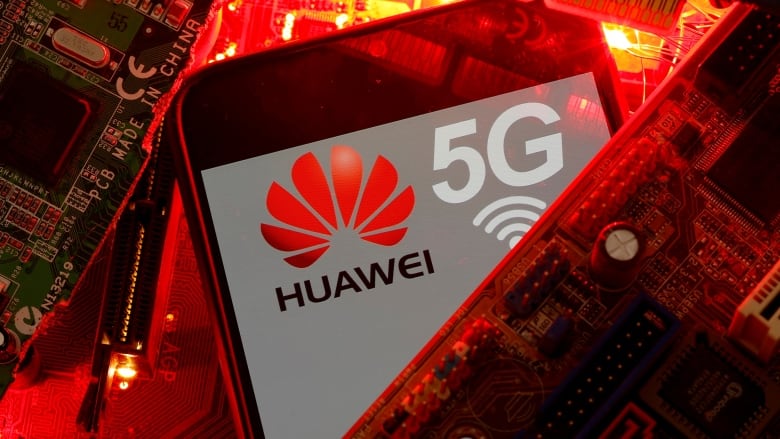 A cellphone with a logo and text reading Huawei 5G sits on a background of computer chips.