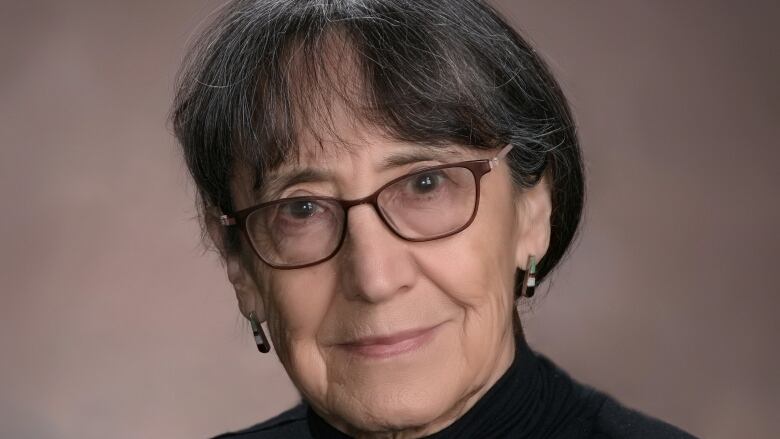 Photo of a woman wearing glasses and a dark turtleneck 