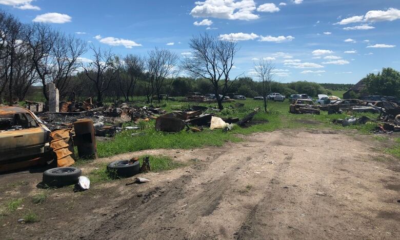 A piece of lawn covered with tires, burned out cars and other items.