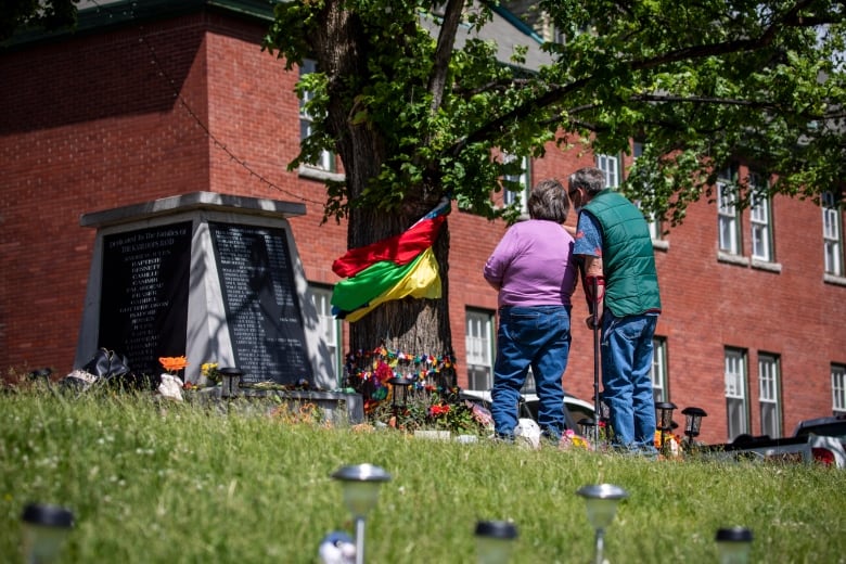 Two people stand at a memorial