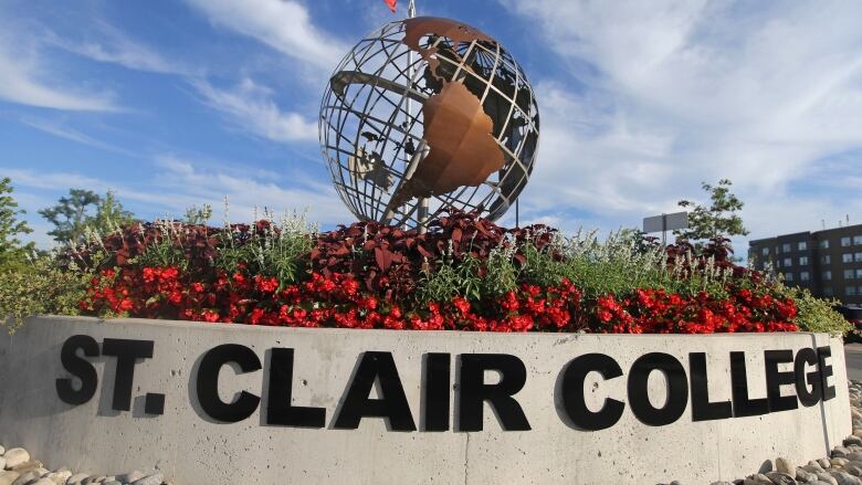 A sculpture of a globe in front of a sign that says St. Clair College.