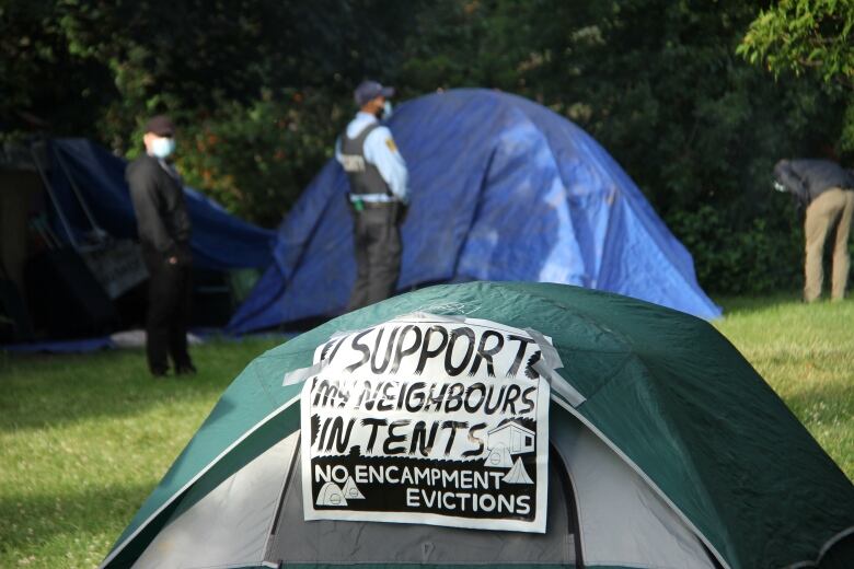 A sign on a tent in a public park reads 