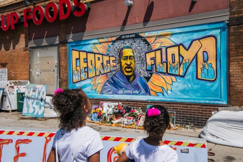 Two children look at a mural.