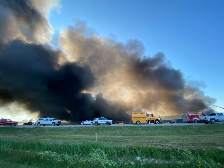 Police and fire trucks are seen on the street with heavy black smoke billowing behind them.