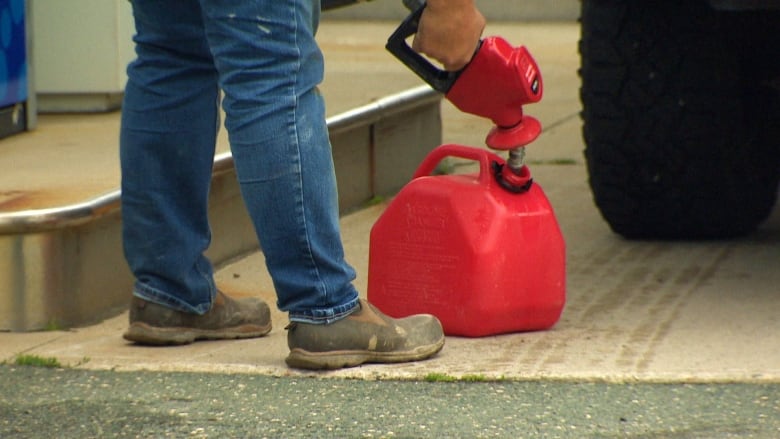 A man pumps gas into a red gas tank.