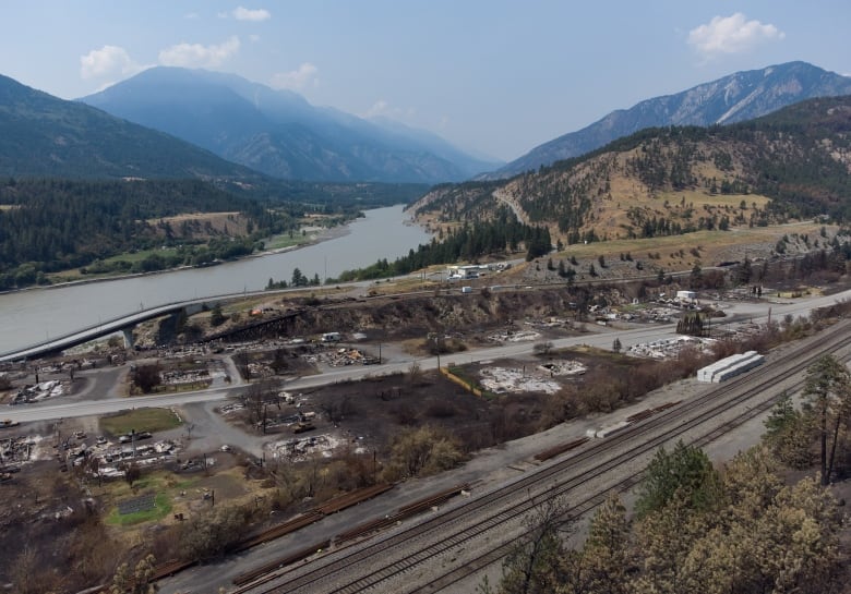 An aerial view of a village damaged by wildfire is shown.