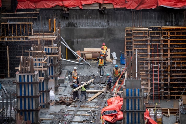 Workers move lumber at a condo construction site in Toronto on March 20, 2020.