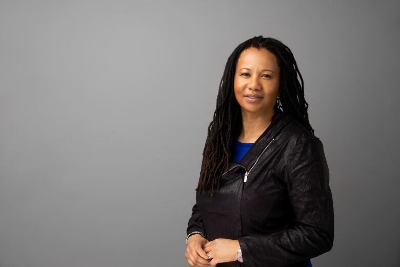 A Black woman with locs wearing a black leather jacket