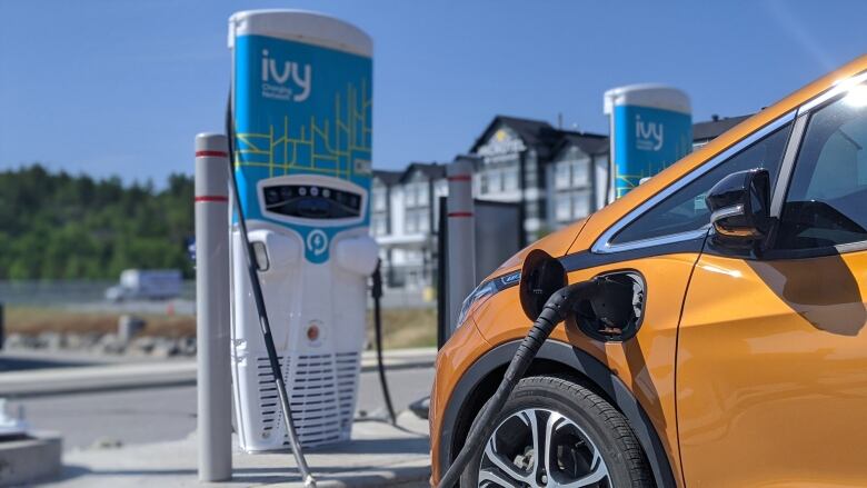 A yellow car charging at a public EV charging station.