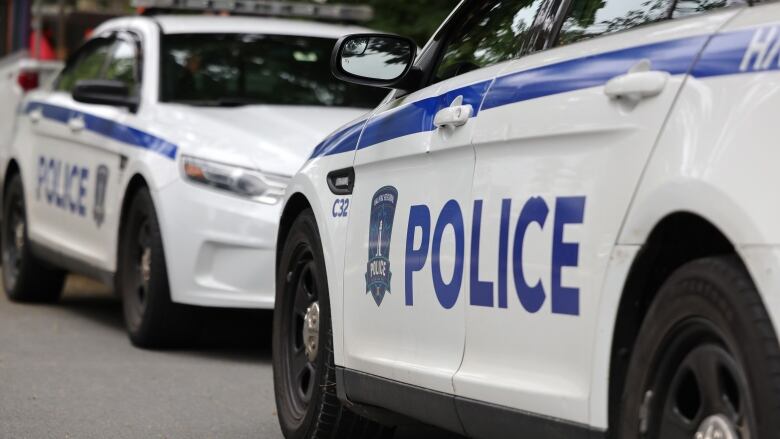 Two police vehicles are parked on a street facing each other. 