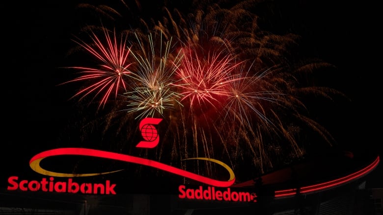 Red and gold streaming fireworks can be seen above a silhouette of the Saddledome.