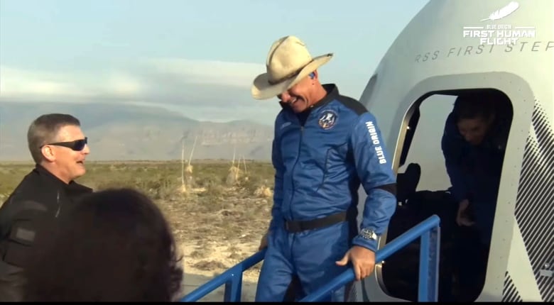 A man in a cowboy hat walks off a spaceship