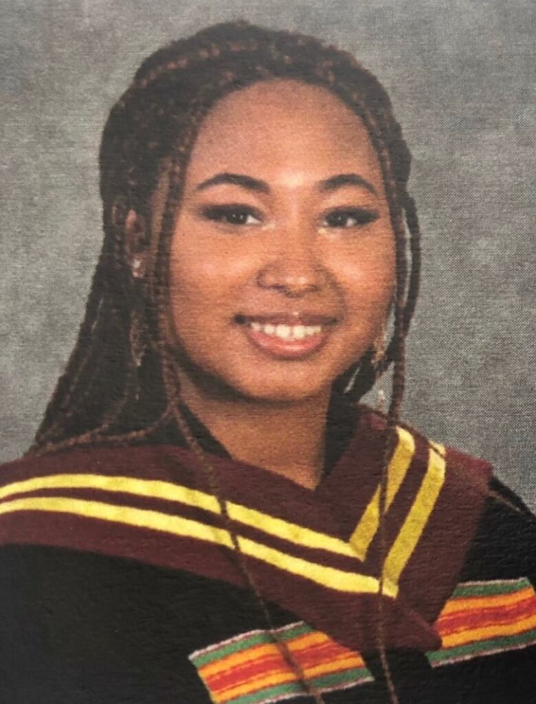 A Black woman with braids wearing a graduation gown