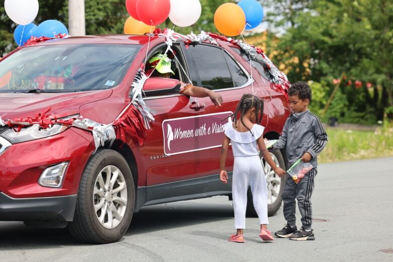 Two children standing beside a car