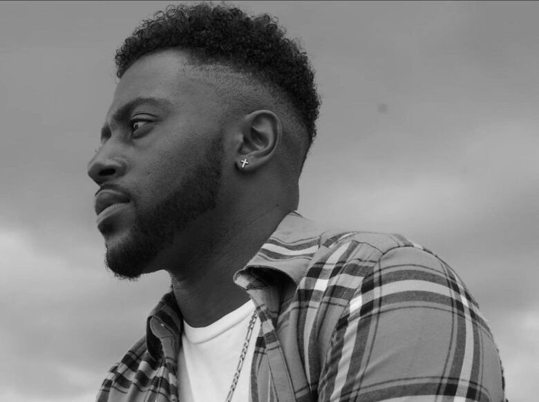 A Black man in profile with a cross earring