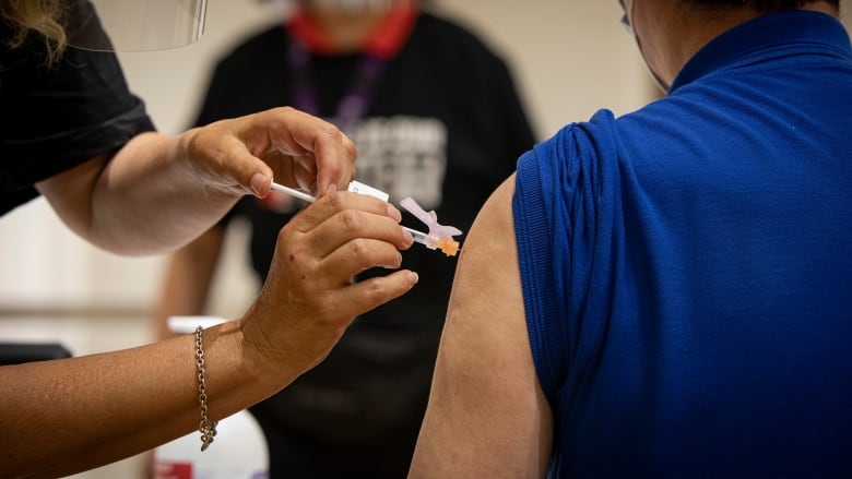 A person gets a COVID-19 vaccination in their shoulder.