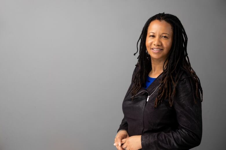 A Black woman with locs wearing a black jacket