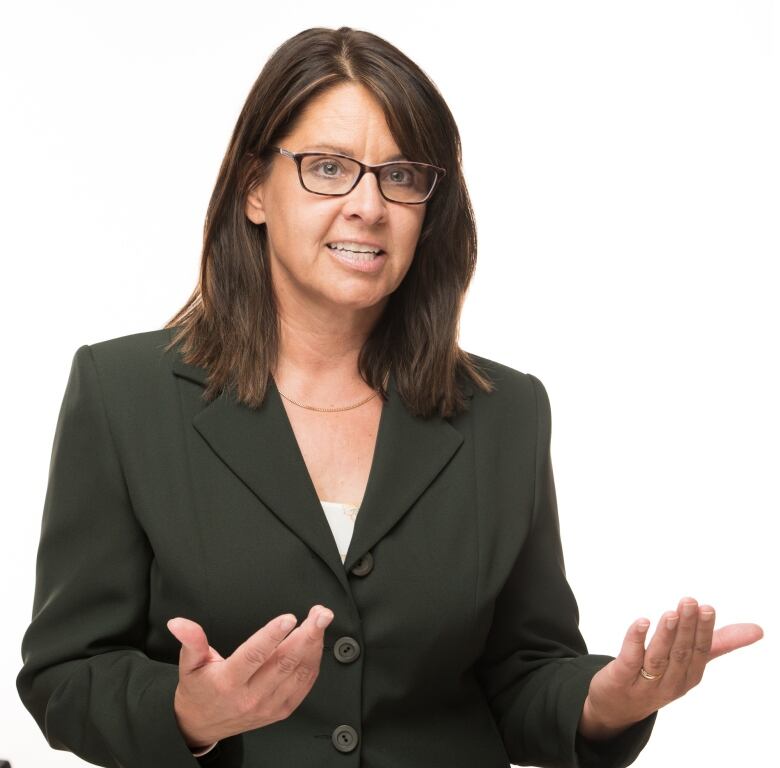 A woman in a blazer gesticulates.