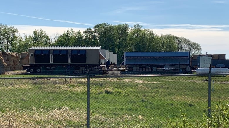 Shipping containers are seen through a fence.