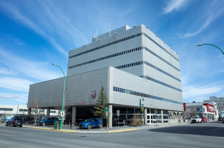 A big gray building sits on the corner. There are several floors and a shoppers drug mart in the background. 