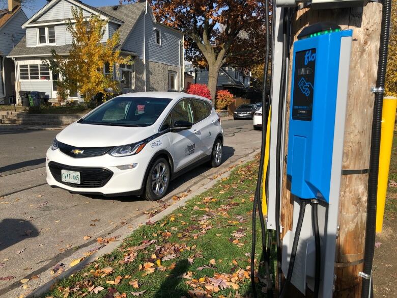 A vehicle charger is shown on a Toronto street with a vehicle parked beside it.