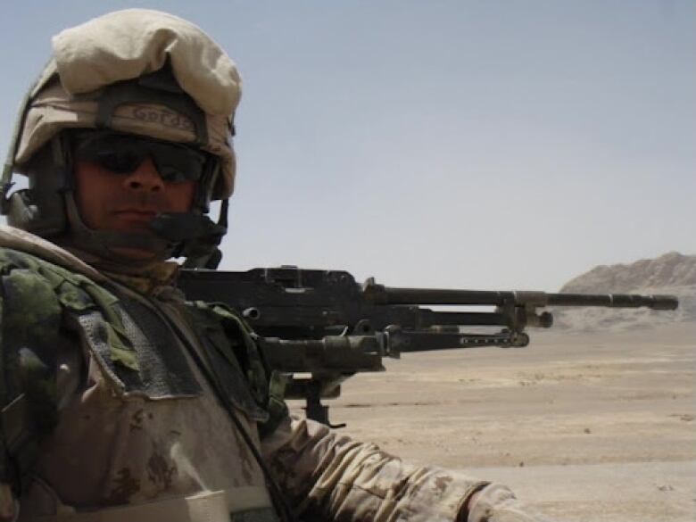 A soldier holds an automatic rifle in the desert.