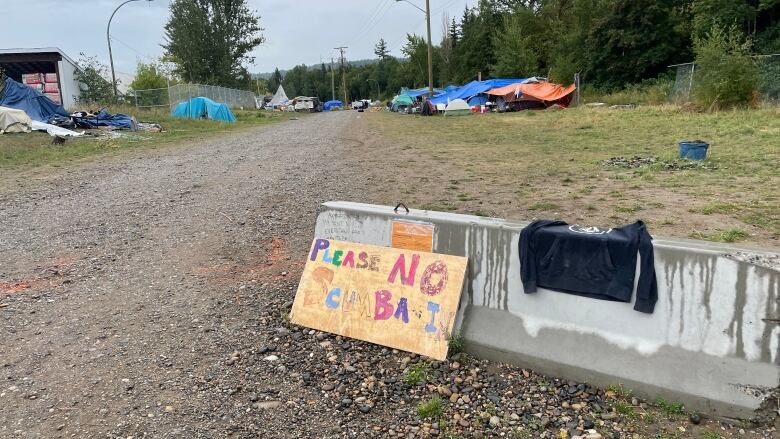 A sign reading 'Please No Scumbags' marks the entrance to a homeless encampment in Prince George, B.C.