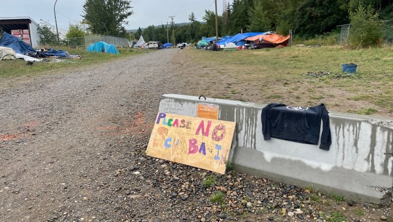 A sign reading 'Please No Scumbags' marks the entrance to a homeless encampment in Prince George, B.C.