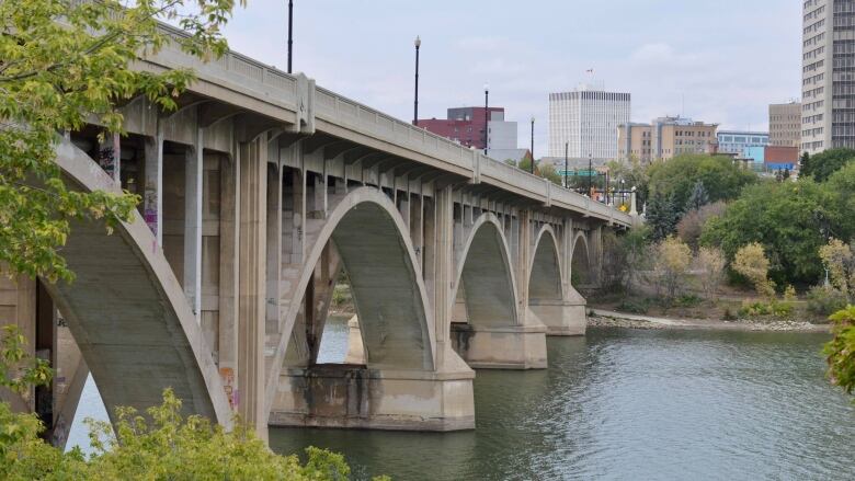 A bridge spans a river, with some downtown-looking buildings in the background.