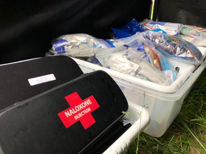 A black Naloxone kit with a red cross sits in a bin next to another bin with medical supplies.