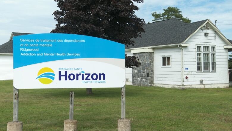 A blue and white sign stands in front of a low white building.