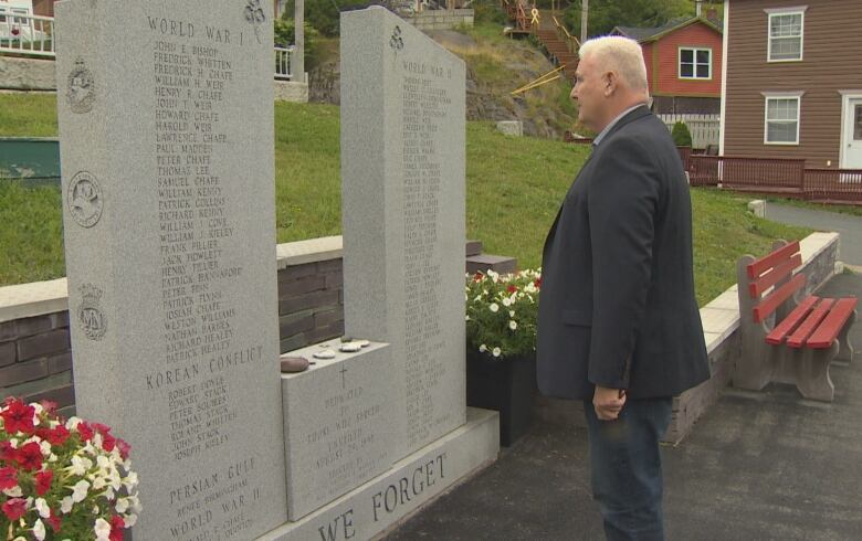 A man stands and looks at a war monument on a foggy summer day in Newfoundland.