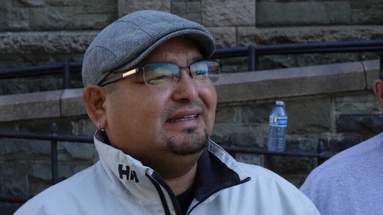 A man wearing eye glasses and a white jacket is smiling.