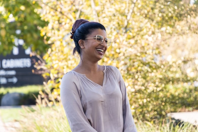 A South Asian woman with black hair smiles.