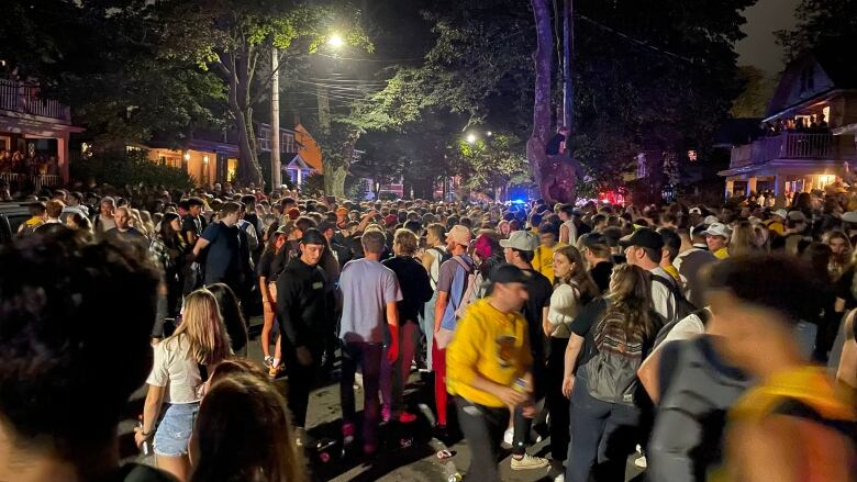 Thousands of young people are shown at a Halifax street party on a dark evening.