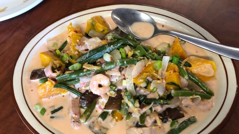 A plate of vegeatables and shrimp covered in a light creamy sauce.