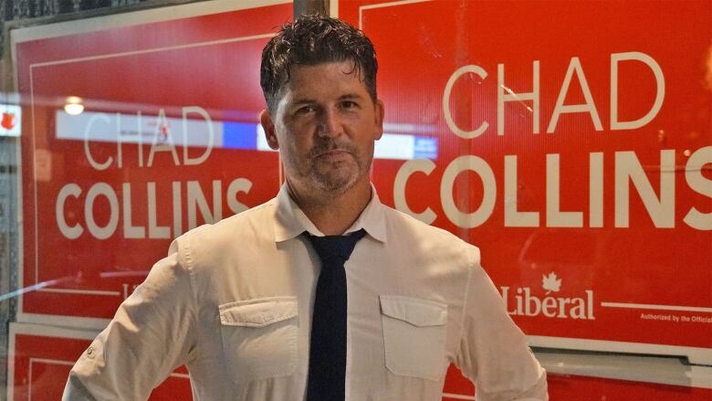 Man stands in front of campaign signs